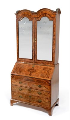 Lot 899 - A Walnut and Feather-Banded Dome Top Bureau Bookcase, the mirrored doors enclosing an...