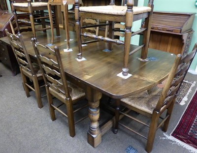 Lot 1323 - A large draw leaf oak dining table and a set of eight beech ladder back chairs