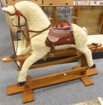 Lot 1428 - A grey fur mounted rocking horse on a treadle base, together with saddle and bridle