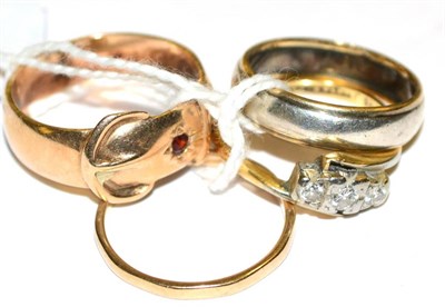 Lot 115 - A diamond three stone twist ring, circa 1930, a garnet set buckle ring, a 9ct gold band ring...