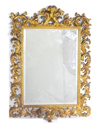 Lot 970 - A Gilt and Gesso Wall Mirror, in rococo style, the bevelled glass mirror plate within an...