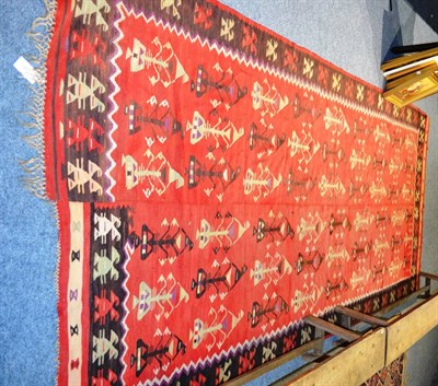 Lot 1139 - Red ground Kilim, probably European Turkey, the tomato field of stylised plants enclosed by...