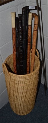 Lot 1110 - Collection of eight African sticks and staffs in a wicker holder