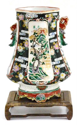 Lot 19 - A Chinese famille vert/noir vase on wood stand