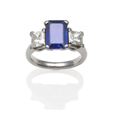 Lot 176 - A Sapphire and Diamond Ring, an emerald-cut sapphire flanked each side by a princess cut diamond in