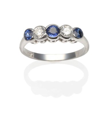 Lot 183 - A Sapphire and Diamond Five Stone Ring, three graduated round cut sapphires spaced by round...