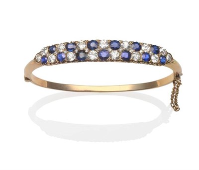 Lot 263 - A Sapphire and Diamond Bangle, two rows of alternating round cut sapphires and old cut diamonds, in