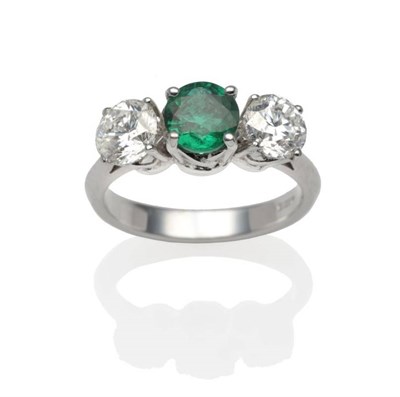 Lot 279 - An 18 Carat White Gold Emerald and Diamond Three Stone Ring, a round cut emerald between two...