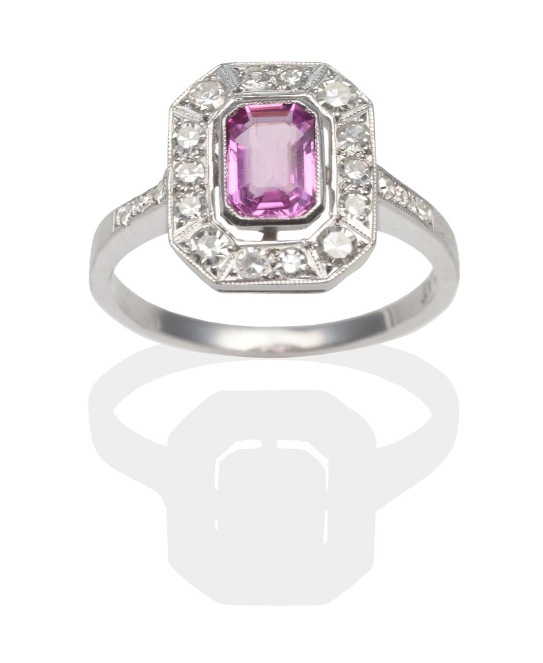 Lot 298 - A Pink Sapphire and Diamond Cluster Ring, an emerald-cut pink sapphire within a conforming...