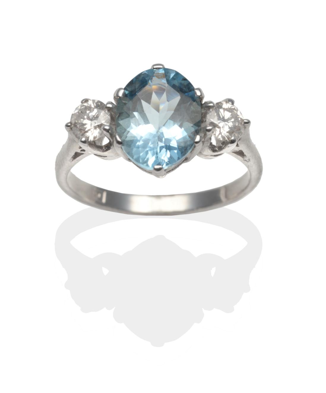 Lot 300 - An Aquamarine and Diamond Three Stone Ring, an oval cut aquamarine between two round brilliant...