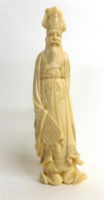 Lot 137 - A Japanese Ivory Okimono of a Court Official, Meiji period, the standing bearded figure wearing...