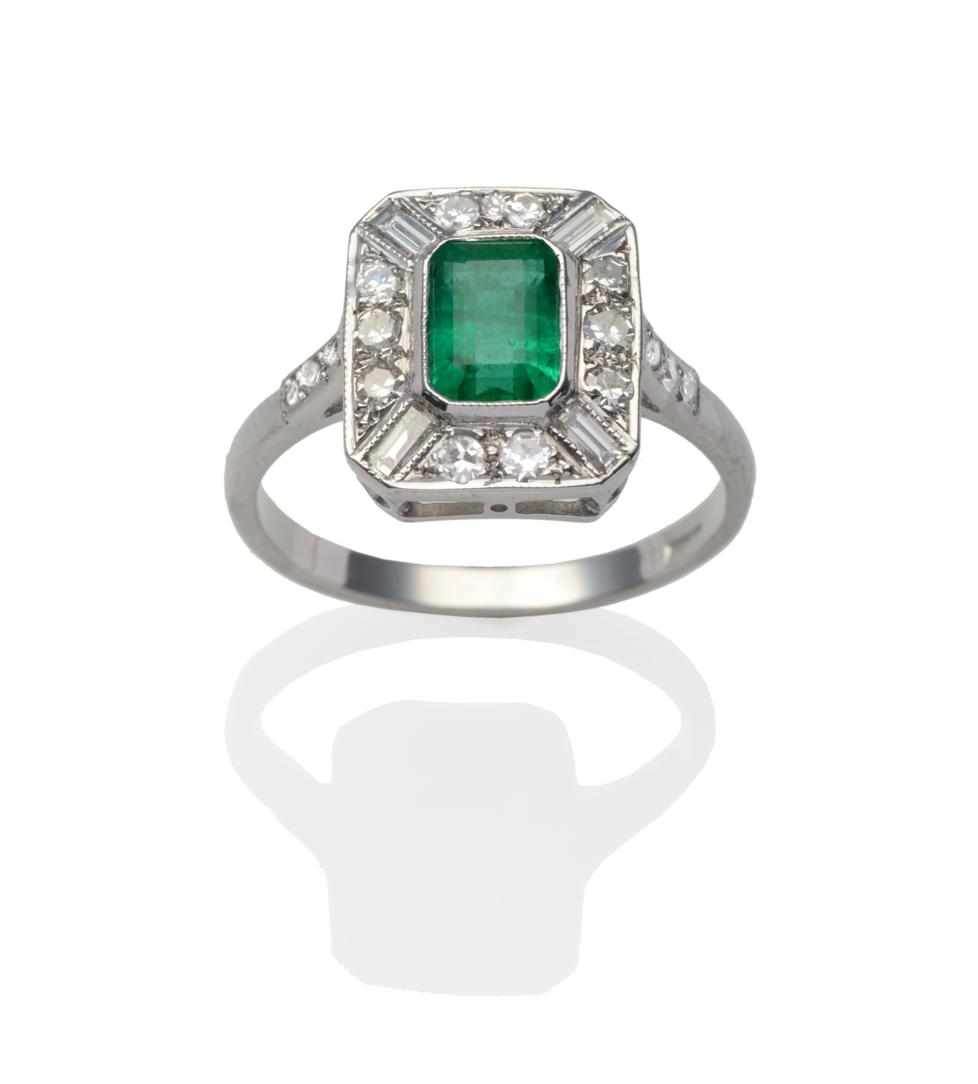 Lot 316 - An Emerald and Diamond Cluster Ring, the emerald-cut emerald within a border of baguette cut...