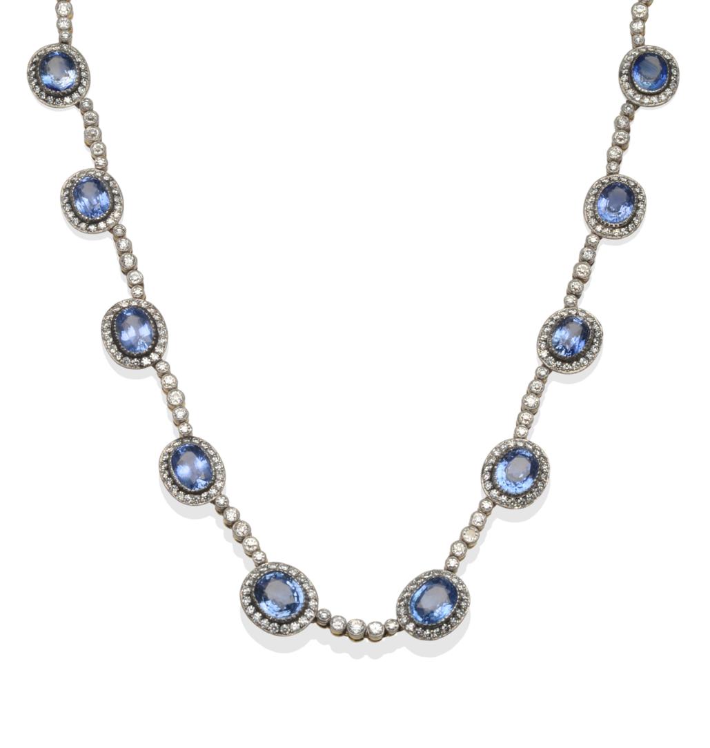 Lot 385 - A Sapphire and Diamond Necklace, thirteen clusters of oval mixed cut mid-blue sapphires within...