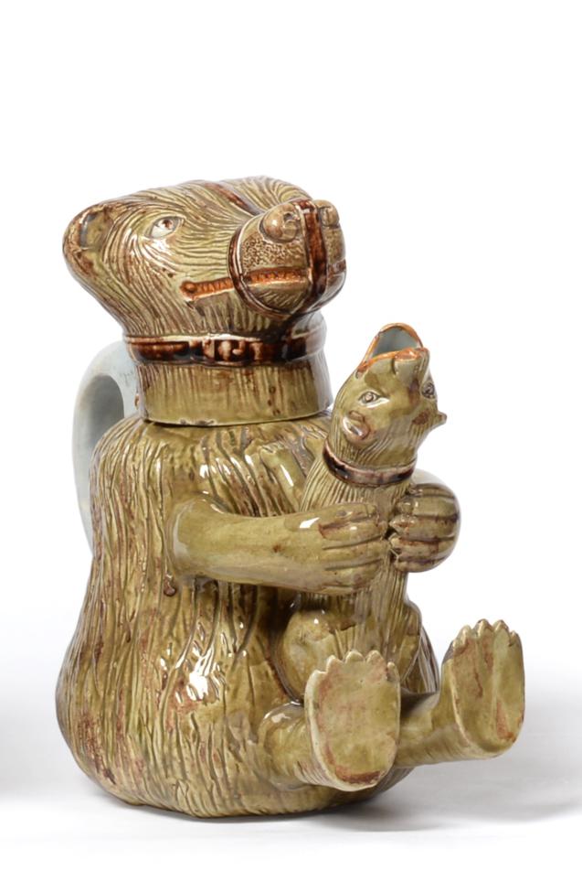 Lot 12 - A Pratt Type Pottery Bear Jug and Cover, circa 1800, naturalistically modelled holding a dog in its