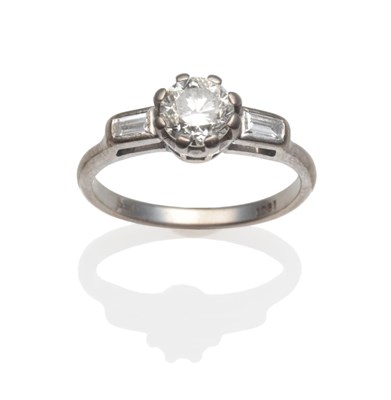 Lot 153 - A Diamond Solitaire Ring, a round brilliant cut diamond in a white claw setting, with baguette...