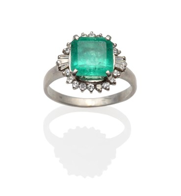 Lot 221 - An Emerald and Diamond Cluster Ring, the square step cut emerald, with truncated corners,...