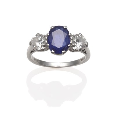 Lot 252 - A Platinum Sapphire and Diamond Three Stone Ring, the oval mixed cut sapphire between two round...