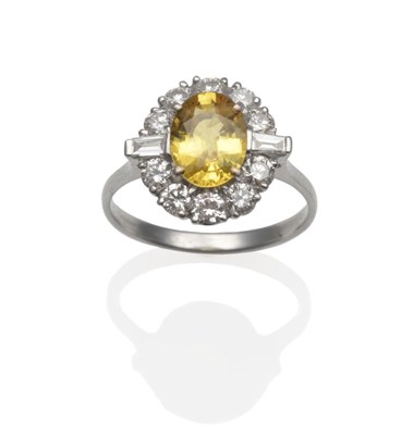 Lot 255 - An 18 Carat White Gold Yellow Sapphire and Diamond Ring, the oval mixed cut sapphire within a...