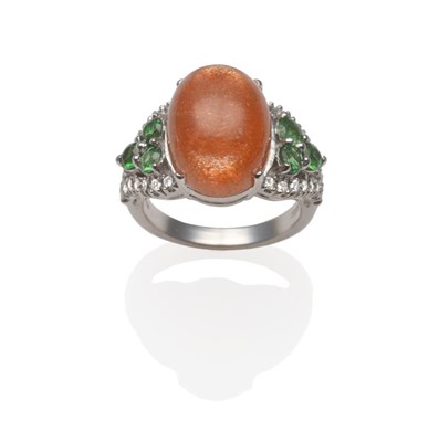 Lot 257 - An 18 Carat White Gold Sunstone, Green Garnet and Diamond Ring, the cabochon sunstone with a...