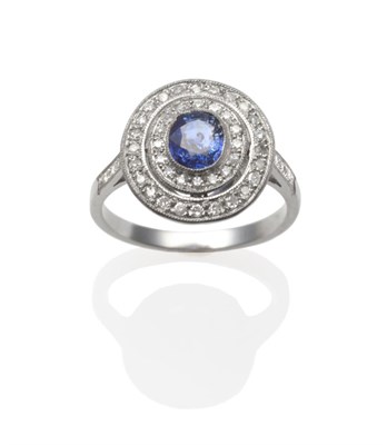 Lot 287 - A Sapphire and Diamond Cluster Ring, the oval mixed cut sapphire within two borders of...