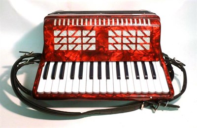 Lot 1194 - A Small Piano Accordion, with red pearlised body, leather straps, in a hard case