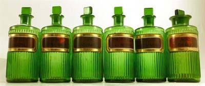 Lot 1073 - Twelve Green Glass Chemists' Rounds, with ribbed bodies, verre eglomise labels and stoppers