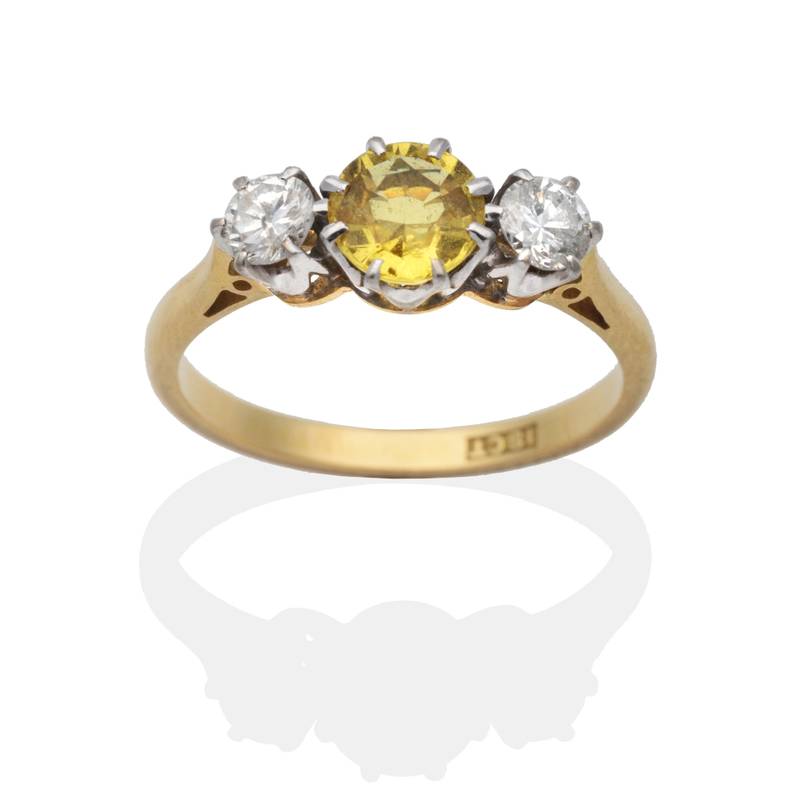 Lot 2064 - A Yellow Sapphire and Diamond Three Stone Ring, a round cut yellow sapphire spaced by round...