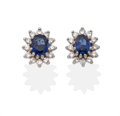 Lot 2127 - A Pair of 18 Carat Gold Sapphire and Diamond Cluster Earrings, an oval cut sapphire within a border