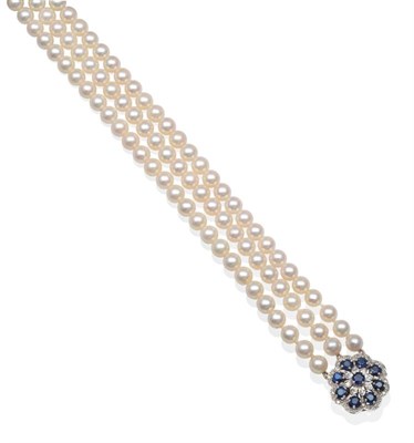 Lot 2128 - A Triple Strand Cultured Pearl Necklace with a 9 Carat White Gold Sapphire Clasp, uniform...