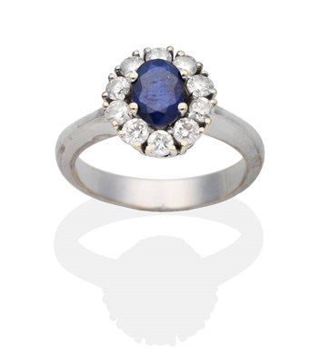 Lot 2132 - A Sapphire and Diamond Cluster Ring, an oval cut sapphire within a border of round brilliant...