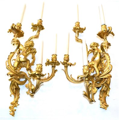 Lot 1015 - A Pair of Gilt Bronze Four-Branch Wall Lights, 19th century, as a cherub amongst four scroll...