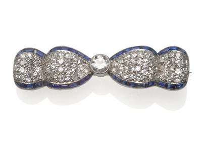 Lot 207 - A Belle Epoque Diamond and Sapphire Bow Brooch, an old cut diamond centres an undulating ribbon...
