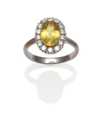 Lot 248 - An 18 Carat White Gold Yellow Sapphire and Diamond Ring, an oval mixed cut yellow sapphire within a