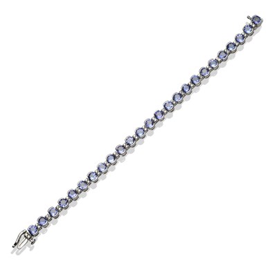 Lot 294 - A Tanzanite and Diamond Bracelet, twenty-five round cut tanzanites alternate with pairs of...