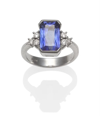 Lot 296 - A Tanzanite and Diamond Ring, an emerald-cut tanzanite in a white broad claw setting, flanked...