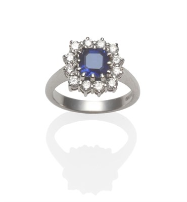 Lot 377 - A Platinum Sapphire and Diamond Cluster Ring, an octagonal step-cut sapphire within a border of...