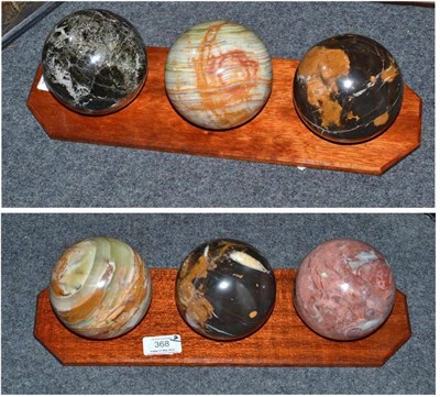 Lot 368 - Two Sets of Three Polished Marble Spheres, each 10cm diameter, on polished wood octagonal stands