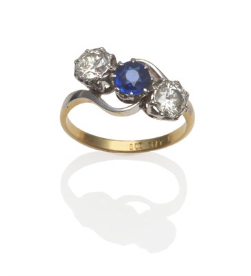 Lot 403 - A Sapphire and Diamond Three Stone Ring, the round cut sapphire between two round brilliant cut...