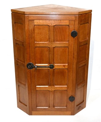 Lot 598 - A Robert  "Mouseman " Thompson Panelled Oak Hanging Corner Cupboard, the interior fitted with three