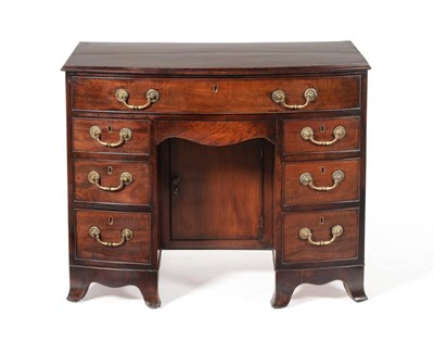 Lot 986 - A George III Mahogany Bowfront Kneehole Dressing Table, circa 1800, the moulded top above a...