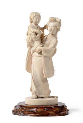 Lot 137 - A Japanese Ivory Okimono, Meiji period, as a mother in traditional robes carrying a child playing a