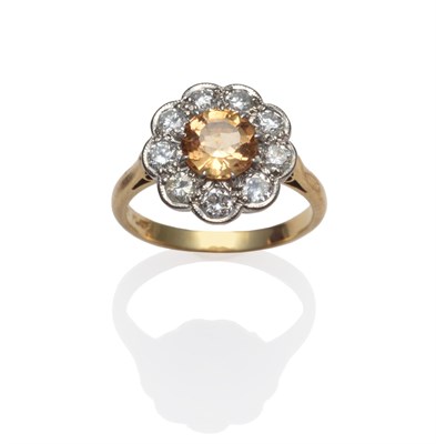 Lot 191 - A Topaz and Diamond Cluster Ring, the round step cut golden coloured topaz within a border of round