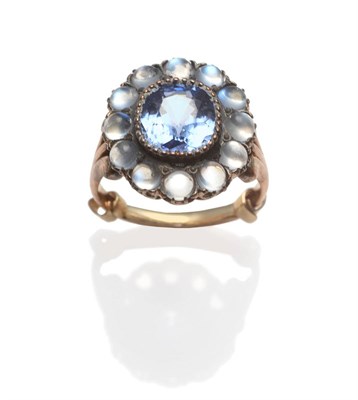 Lot 262 - A Sapphire and Moonstone Cluster Ring, the cushion cut sapphire within a border of round...