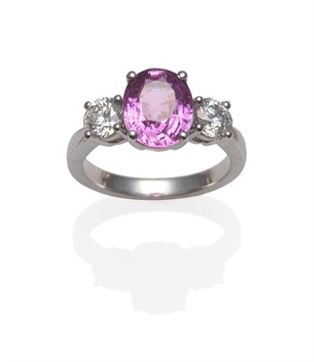 Lot 334 - A Platinum Pink Sapphire and Diamond Three Stone Ring, the oval mixed cut pink sapphire between two