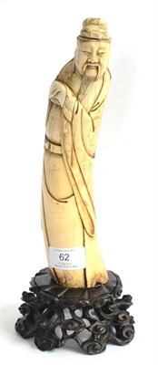 Lot 62 - A Chinese Carved Ivory Figure of a Sage, 17th century, the bearded figure wearing a cap and...