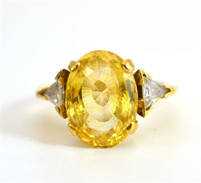 Lot 145 - An 18 Carat Gold Yellow Sapphire and Diamond Three Stone Ring, the oval cut light yellow...