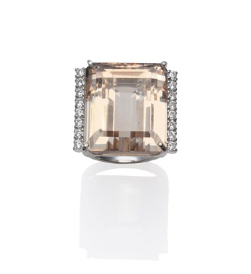 Lot 149 - An 18 Carat White Gold Topaz and Diamond Ring, the emerald-cut peachy coloured topaz with a row...