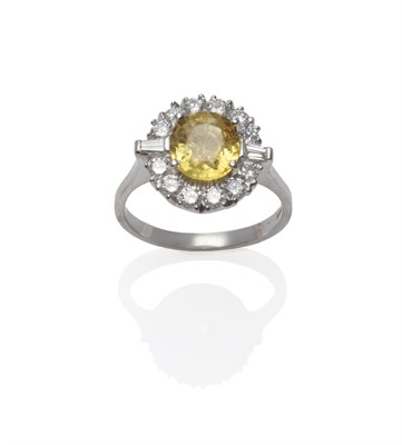 Lot 156 - An 18 Carat White Gold Yellow Sapphire and Diamond Ring, the oval mixed cut sapphire within a...