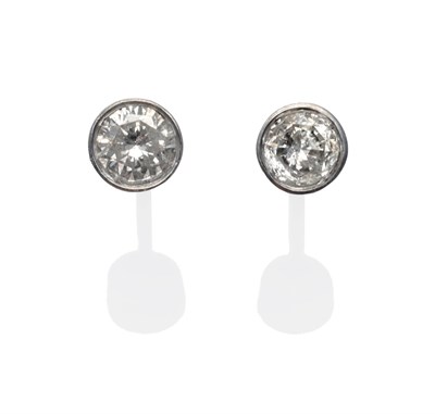 Lot 220 - A Pair of Diamond Solitaire Earrings, each round brilliant cut diamond in a white rubbed over...