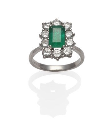 Lot 257 - An Emerald and Diamond Cluster Ring, an emerald-cut emerald within a border of round brilliant...